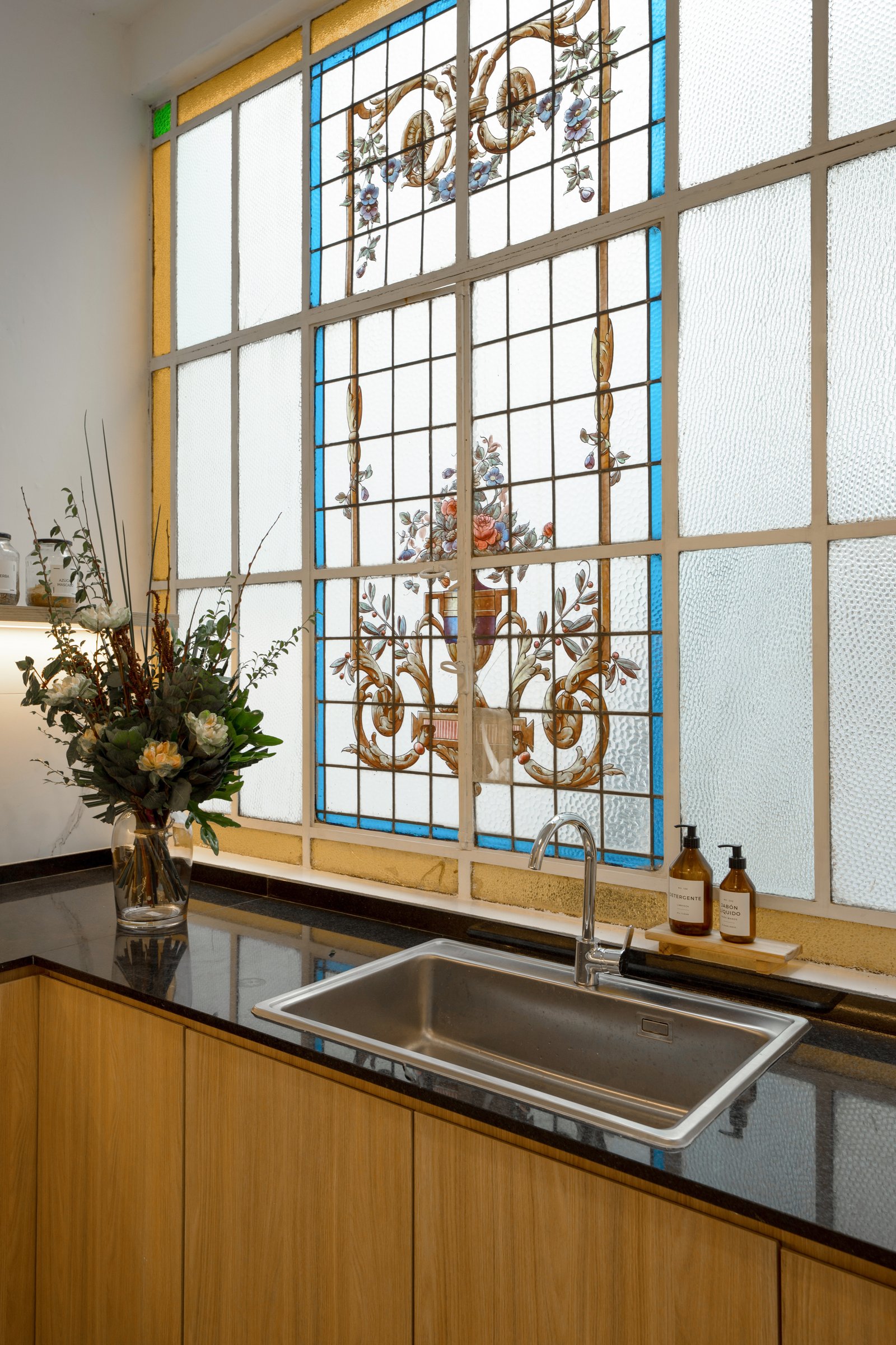 Cozinha moderna com vitral e bancadas de pedra preta — projeto Casa Gainza, por Estudio Plats, em Caballito